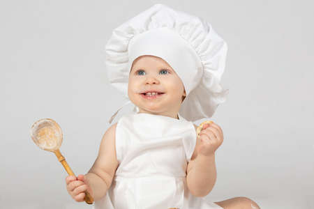 Beautiful baby bathes in a basin and eats a red apple. Little girl in one year old.の写真素材