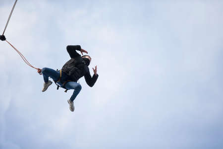 Belarus, Gomel, March 08, 2019. Jumping from the bridge to the rope.Ropejumping.Dangerous hobbies.Woman jumping down from a great height in a frog poseのeditorial素材