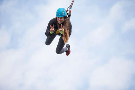 Belarus, Gomel, March 08, 2019. Jumping from the bridge to the rope.Ropejumping.Dangerous hobbies.Brave woman jumping from the bridge against the skyのeditorial素材