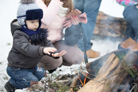 Belarus, Gomel, February 18, 2018. Russian holiday seeing off winter Maslenitsa.A boy is warming his hands at the stake.warm hands with fireのeditorial素材