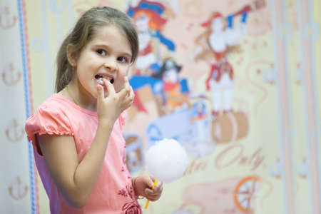 Belarus, Gomel, on March 10, 2018. Children's holiday at the opening of the store Caravan. Girl is eating sweet airy cotton.sweet cotton wool to eatのeditorial素材