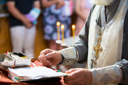 Orthodox religion. Hands of the priest against the background of the cross and candles.の写真素材