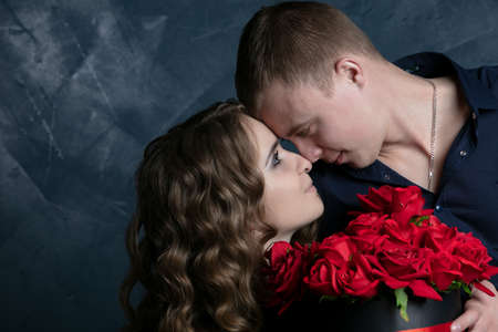 Beautiful young couple .Hugs, kisses and enjoys spending time together, celebrating Valentines Day with red roses.の写真素材
