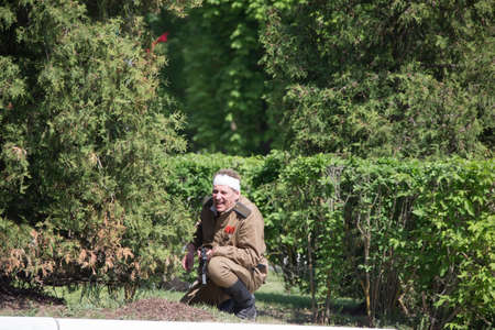 Belarus, Gomel. May 9, 2018. Victory Day. Historical reconstruction in 1945, capture of the Reichstag. Russian soldier of World War II sitting in the bushesのeditorial素材