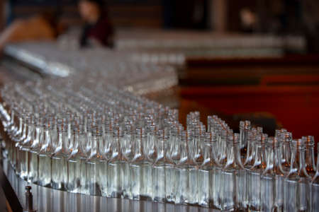 Glassworks. Glass industry. Many glass bottles on a factory conveyor.の写真素材