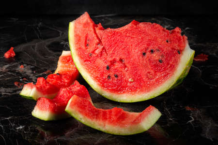 Half a watermelon with stubs on a dark background