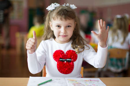 Belarus, the city of Gomil, May 10, 2019. Open day in kindergarten.Child preschooler with book on class background. Girl schoolboy primary school. Portrait of a six year old child. Little student.のeditorial素材