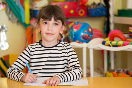 Belarus, the city of Gomil, April 26, 2019. Open day in kindergarten.Child preschooler with book on class background. Girl schoolboy primary school. Portrait of a six year old child. Little student.のeditorial素材