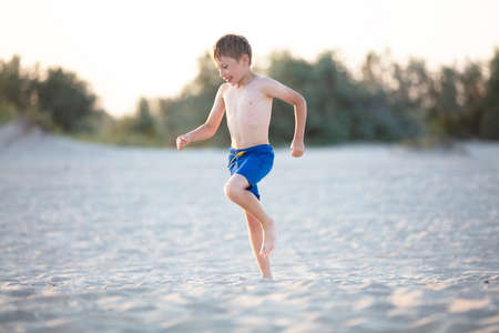 A child plays on the sandy shore. Boy playing on the beachの写真素材