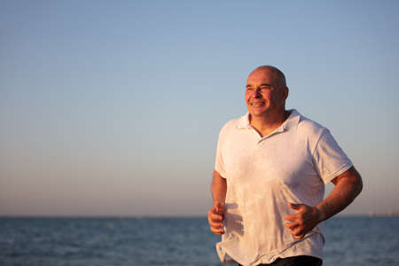 An elderly man runs along the sea. Jogging at the resort.の写真素材