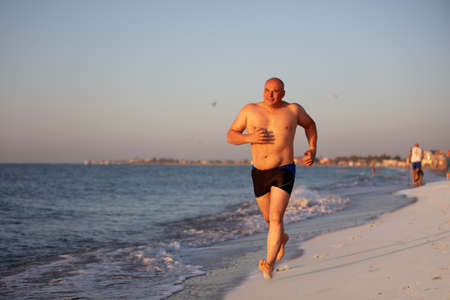 An elderly man jogs along the coast.の写真素材