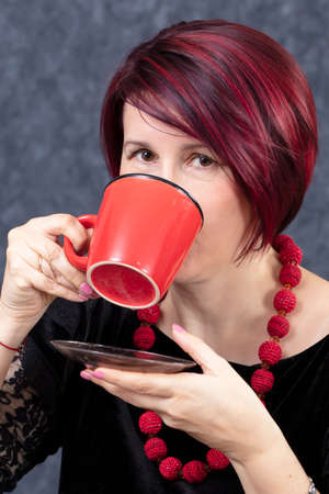 A woman is drinking from a red cup.の写真素材