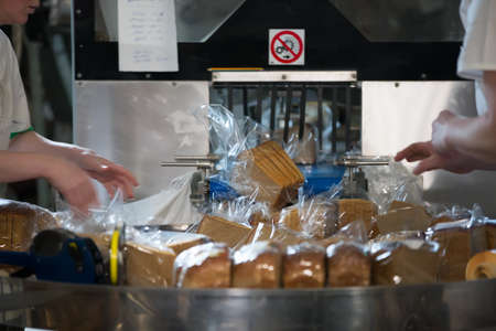 Industrial line for packaging of bakery products. Packing of bread at the factory. The machine for...