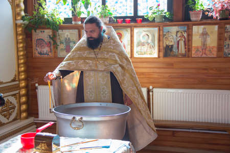 Belarus, Gomel, September 17, 2018. Prudkovsky church. The baptism of the child. Orthodox priest blesses the font for baptism.のeditorial素材