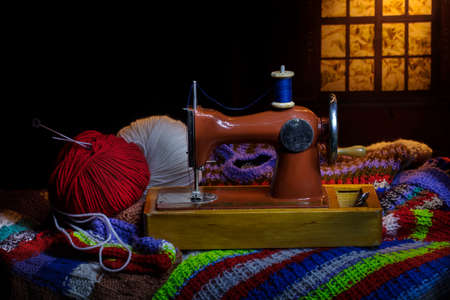 Old sewing machine clews and knitting needles on a dark background