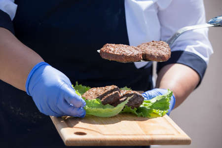 Hamburger cutlets in the hands of the chef. The process of making a hamburger.