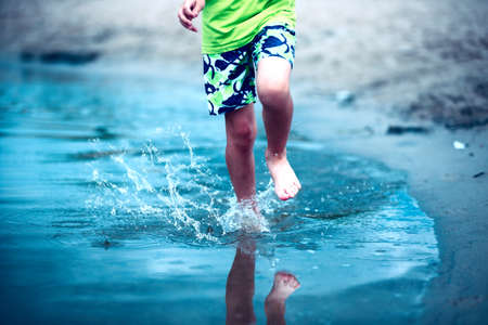 Children's feet run through the water spraying water.