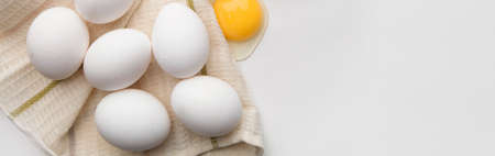 Lots of eggs and a broken egg on the tea towel.の写真素材