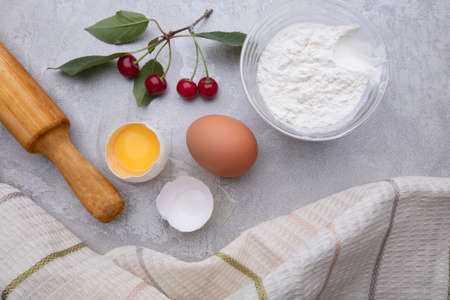 Ingredients baking flour eggs rolling pin berries kitchen textiles on gray background. Cookie pie or cake recipe mockup. Background preparation for culinary baking.の写真素材