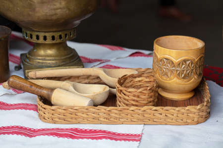 Wooden ethnic spoon and cup on a tray of vinesの写真素材