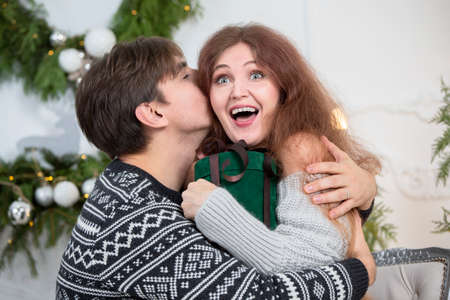 A man gives a woman a Christmas present. Husband and wife in the New Year holidays. Get a surprise in the winter holidays. Christmas holidays concept.の写真素材