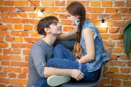 A guy and a girl in jeans clothes on a background of a brick wall on a background of a brick wall