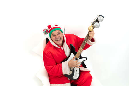 Santa Claus with an electric guitar from a hole in paper. Christmas Holidays. Man in a New Years...