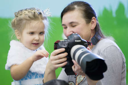 Belarus, the city of Gomil, December 26, 2016. Parent day in kindergarten.The photographer shows the camera to a little girl. Childrens photographer.のeditorial素材