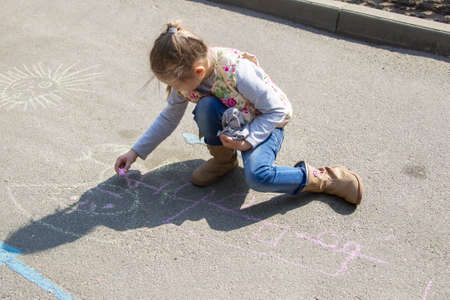 Belarus, Gomel, May 30, 2019. An open day in a kindergarten. A preschool girl draws on the asphalt with chalk.のeditorial素材