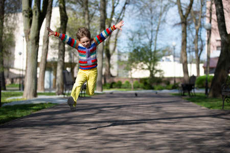 Happy child is jumping up for a walk in the park.の写真素材