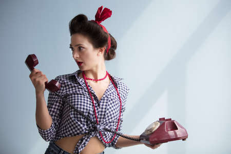Retro girl with a phone. Pin-up woman with a telephone receiver.Emotion of surprise on the face.の写真素材