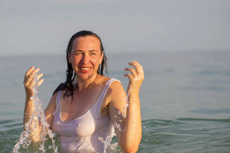 Elderly woman in sea water. Middle-aged woman bathing in the ocean.
