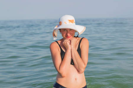 Woman in middle-aged hat in bikin at sea