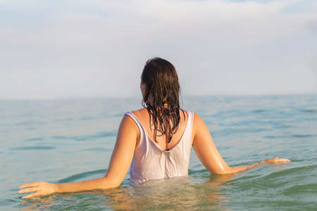 A woman in a shirt goes into the water.Woman in sea waterの写真素材