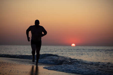 Silhouette of a male athlete on a background of sunrise at sea