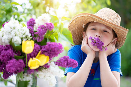 Cheerful child in a straw hat with a lilac. Happy boy in the summer.の写真素材