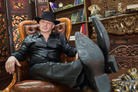 Elderly man in a hat in a leather chair