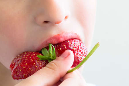 Man eats strawberries. Berry in the mouth. Small child or baby eating red color berry of strawberry
