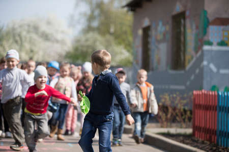 Belarus, the city of Gomel, April 25, 2019. kindergarten central. Open day. The child runs away from children. A crowd of preschoolers chasing a boyのeditorial素材