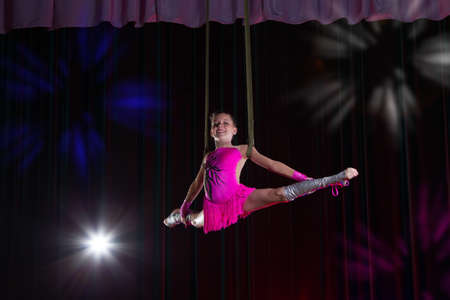 Circus artist acrobat performance. The girl performs acrobatic elements in the air. Circus gymnast on the stageの写真素材