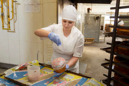 Belarus, the city of Gomil, April 25, 2019. Bakery.A bakery worker decorates Easter cake. Industrial...