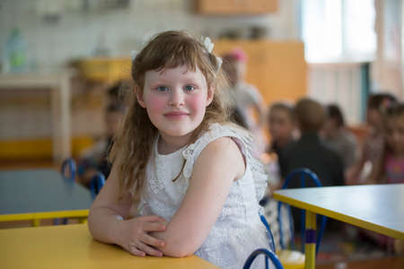 Belarus, the city of Gomel, April 26, 2019. Open day in kindergarten. Girl preschooler. Portrait of a six year old child. Junior student at her desk.のeditorial素材