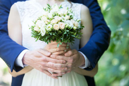 Wedding bouquet in the hands of the bride and groom. Marriage Hands of lovers on before the weddingの写真素材