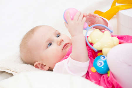Newborn baby examines rattles. Six month old girl with toysの写真素材