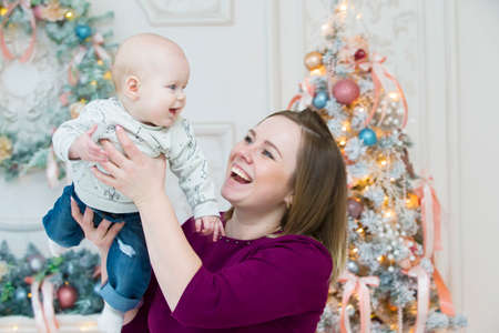 Mom with a child on the background of a New Year tree. Mother and son at christmas.