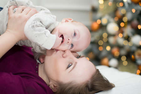 Mom with a child on the background of a New Year tree. Mother and son at christmas.