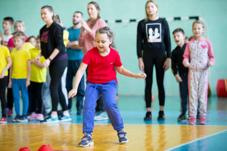 Belarus, the city of Gomil, December 07, 2019. Open physical education lesson. The girl participate in a sports day. Childrens relay. Primary school students are competing.のeditorial素材