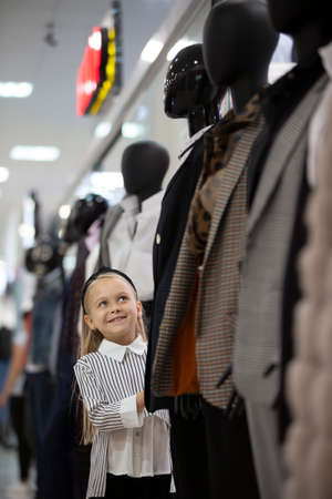 A little girl in the middle of a dummy in a store.の写真素材