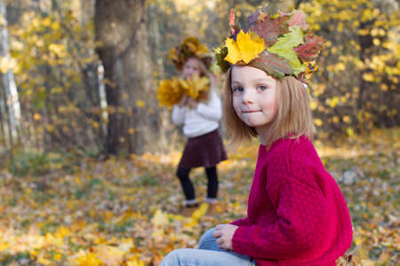 Girl in autumn park with a wreath of maple leaves