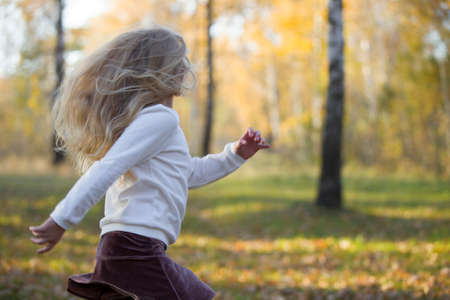 Blurred Beautiful girl runs in the autumn forestの写真素材